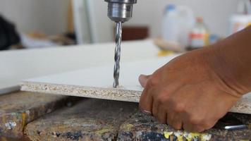 Carpenter hand holding a wooden table while drilling with a drill photo