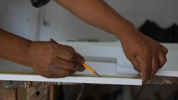 Hands carpenter taking measurements on a white wooden table in his workshop photo