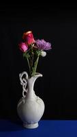 Flowers in old white ceramic vase on dark background in vertical format photo