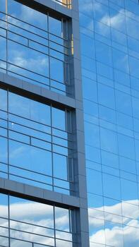 Approach to the glass windows reflecting a blue sky of a modern building. Abstract background photo