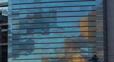 Approach to the glass windows reflecting a blue sky of a modern building. Abstract background photo