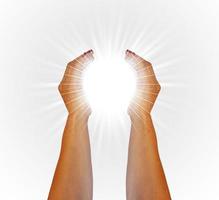 Rays of white light between the hands of a woman on white background photo