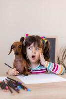 cute little girl draws with her friend dog dachshund. Children and animals. Dog Friendly. High quality photo