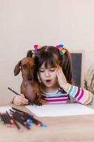 cute little girl draws with her friend dog dachshund. Children and animals. Dog Friendly. High quality photo