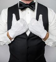 Portrait of Waiter or Butler  in Black Waistcoat and White Gloves Standing Elegantly. Concept of Service Industry and First Class Hospitality. photo