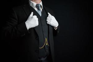 retrato de mayordomo con traje oscuro y guantes blancos de pie con orgullo. concepto de industria de servicios y cortesía profesional. foto