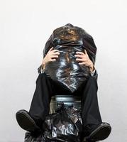 Portrait of Man Sitting in Trash Can Crushed by Rubbish. Concept of Human Waste and Garbage Person. photo