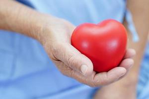 Asian elder senior woman patient holding red heart in hospital. photo