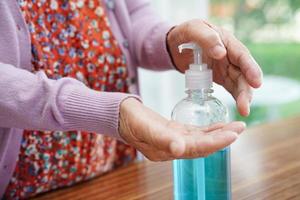 mujer mayor asiática presione gel desinfectante de alcohol azul para lavarse las manos proteger la infección por coronavirus. foto