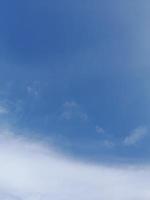 White clouds in the blue sky. Beautiful bright blue background. Light cloudy, good weather. Curly clouds on a sunny day. photo