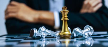 Business strategy. golden king with silver chess piece on chess board game competition on business man background, checkmate, chess battle, victory, success, leadership, teamwork, team leader concept photo