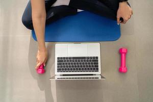 Young asian woman on yoga mat taking exercise class at home photo