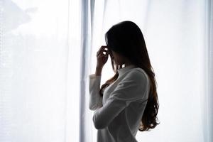 mujer asiática joven estresada que sufre depresión y está sola en una habitación oscura en casa. concepto decepcionado
