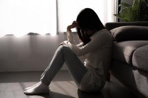 mujer joven que se siente deprimida y estresada sentada en un dormitorio oscuro. concepto de salud mental.