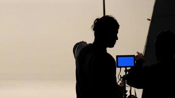 Movie director and photographer are talking or consulting to making studio set before shooting video and silhouette background lighting. photo