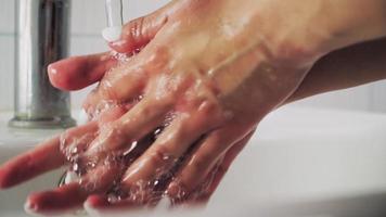 mano de mujer de belleza lávese las manos en el lavabo con espuma, limpie la piel. conceptos de salud y belleza. medidas básicas de protección contra el nuevo coronavirus. de cerca. video