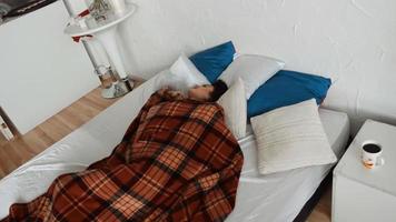 menina doente enrolada em cobertor e mede a temperatura corporal com termomentrom na cama em casa video