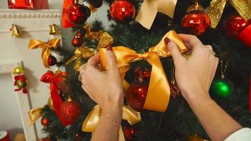 la fille corrige l'arc orange sur l'arbre de Noël à la maison video