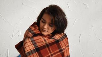 charming brunette stands near a wall and wrapped in a warm blanket with closed eyes video