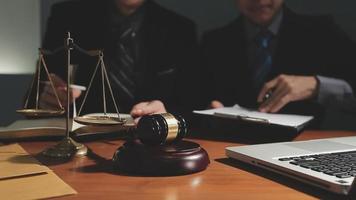 Business and lawyers discussing contract papers with brass scale on desk in office. Law, legal services, advice, justice and law concept picture with film grain effect video