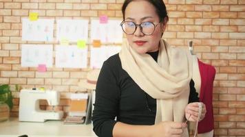 une créatrice de mode asiatique d'âge moyen travaille dans un studio en mesurant des formes de marionnettes et en dessinant des idées de croquis, une collection de conception de vêtements d'imagination, une boutique professionnelle de tailleur PME entrepreneur. video