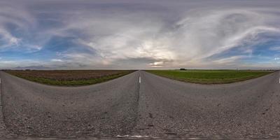 vista panorámica completa esférica hdri 360 sin tráfico en carretera asfaltada entre campos con cielo nocturno y nubes en proyección equirectangular, se puede utilizar como reemplazo del cielo en panoramas foto