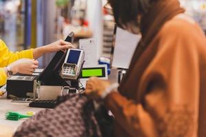 cliente mujer pagando con tarjeta de crédito usando tecnología nfc en centro comercial. foto