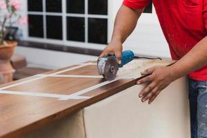manos de carpintero cortando madera con sierra circular eléctrica. foto