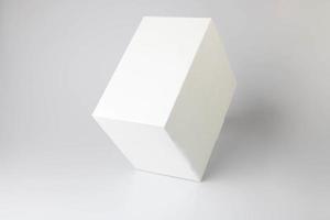 A white cardboard box stands on a white background on the edge photo