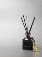 long black fragrant sticks one by one In a luxury opaque glass bottle with essential oils to spread the fragrance gray background There is a text area. photo