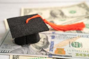 sombrero de la brecha de graduación en el dinero de los billetes en dólares estadounidenses, concepto de enseñanza de aprendizaje de la tarifa de estudio de educación. foto