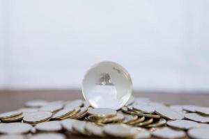 negocio global y concepto financiero, económico y de planificación. primer plano de una mini bola mundial de cristal transparente sobre un montón de monedas con espacio para copiar. foto