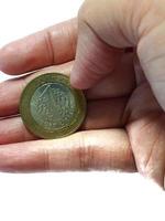 Turkey in June 2022. Isolated white photo of a hand holding a Turkish one lira coin.