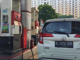 Jakarta, Indonesia in July 2022. A female gas station attendant refuels a white car. photo