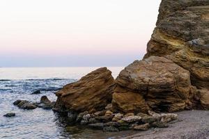 Large stone cliffs on the shore of sea photo