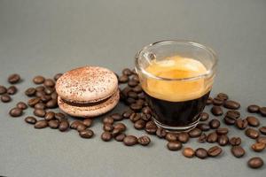 primer plano de una taza de café esparcida granos de café y galletas macarons foto