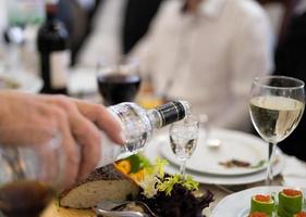 el camarero vierte una bebida alcohólica, vodka en un vaso. foto