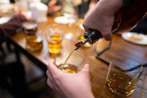 the bartender pours alcohol from the bottle photo