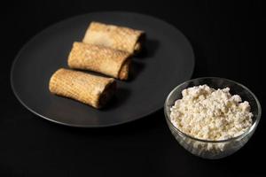 pancakes with cheese on a plate and kitchen utensils on a black background photo