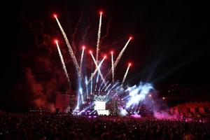 saludo y fuegos artificiales en un escenario musical con focos en la noche. foto