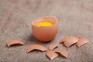 Fresh eggs on sacking, broken eggshell, yolk photo