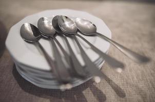 many clean spoons, and a mountain of plates on the table ready for serving. photo