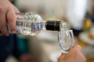 the waiter pours an alcoholic drink, vodka into a glass. photo