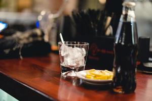 an alcoholic drink with ice is served by the bartender at the bar photo