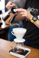 barista pours water from the kettle photo