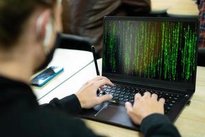 hacker writes code on laptop in matrix style photo