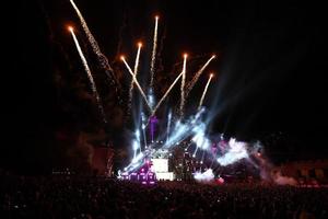 saludo y fuegos artificiales en un escenario musical con focos en la noche. foto