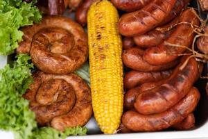 a delicious dish of meat sausages, salad and corn photo