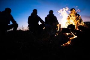 a group of friends gathered around the fire at night photo