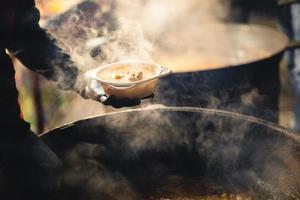 the cook fills a bowl with hot street food photo